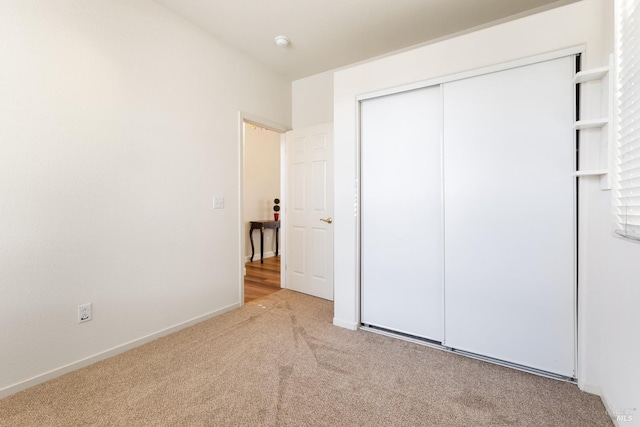 unfurnished bedroom featuring light carpet and a closet