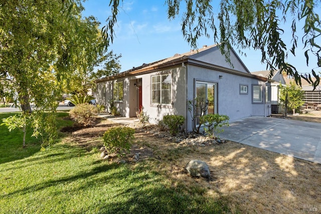 view of front of house featuring a patio, a front lawn, and stucco siding