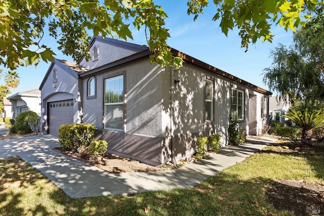 view of front facade with driveway, a garage, and stucco siding