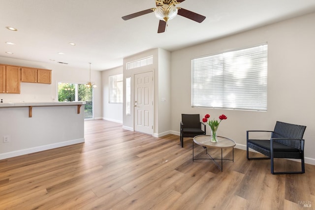 sitting room featuring ceiling fan with notable chandelier and light wood-type flooring