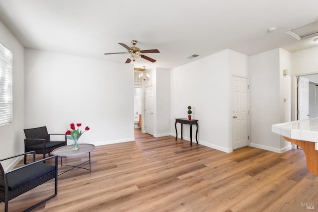 living area with a ceiling fan, baseboards, and light wood finished floors