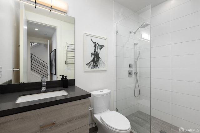 bathroom featuring tiled shower, vanity, and toilet