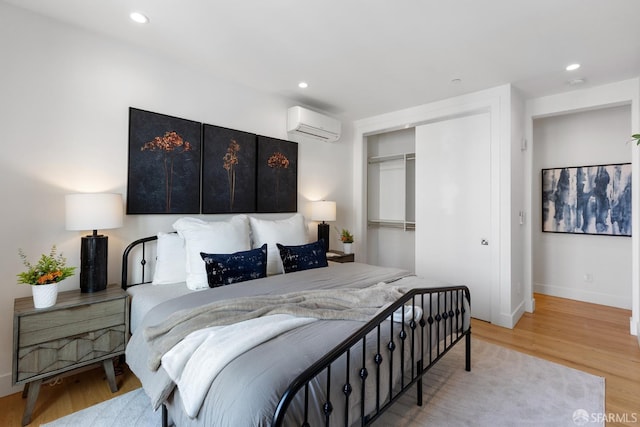 bedroom featuring a wall mounted air conditioner, hardwood / wood-style floors, and a closet