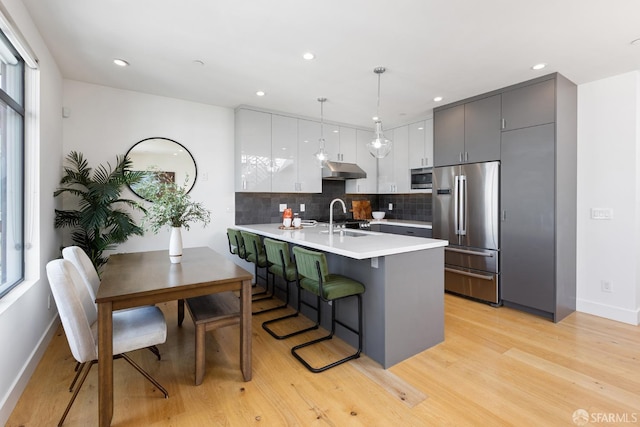 kitchen featuring sink, a breakfast bar area, appliances with stainless steel finishes, pendant lighting, and white cabinets