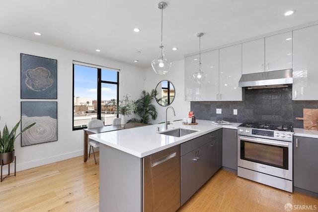 kitchen featuring sink, appliances with stainless steel finishes, white cabinetry, hanging light fixtures, and kitchen peninsula