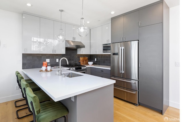 kitchen with gray cabinets, appliances with stainless steel finishes, a kitchen breakfast bar, decorative light fixtures, and kitchen peninsula