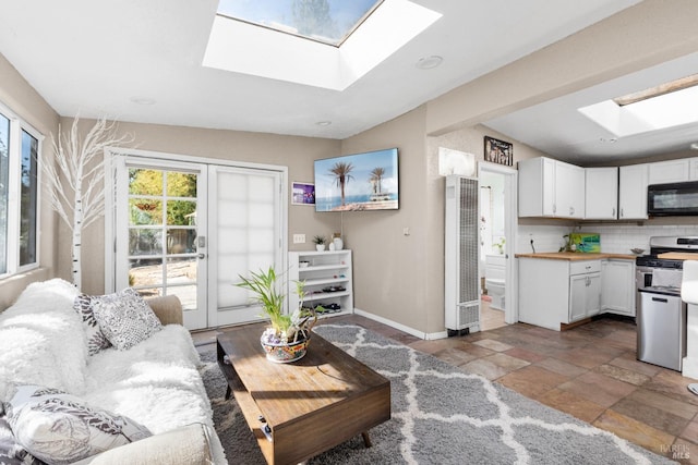 living room with beam ceiling and a skylight