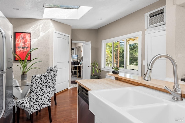 kitchen featuring sink, appliances with stainless steel finishes, a skylight, dark hardwood / wood-style flooring, and an AC wall unit