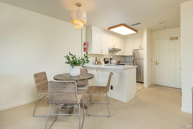 dining space with sink and light colored carpet