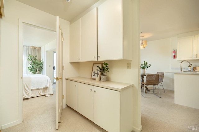 corridor featuring sink and light colored carpet