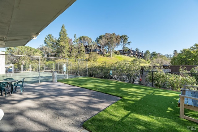 view of home's community with a yard and tennis court