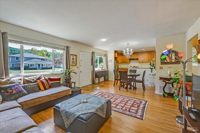 living room with light wood-type flooring, visible vents, a notable chandelier, and baseboards