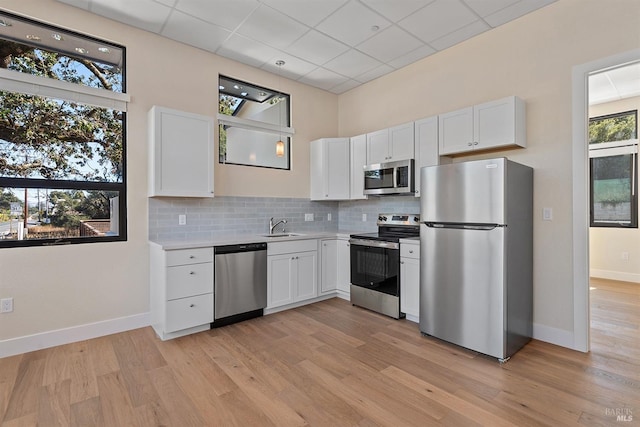 kitchen featuring stainless steel appliances, white cabinets, a wealth of natural light, and a paneled ceiling