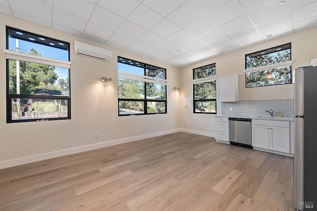 interior space featuring light hardwood / wood-style floors, a healthy amount of sunlight, and a wall mounted AC