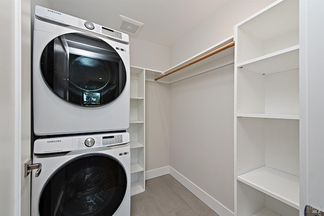 laundry area featuring stacked washer and dryer and light tile patterned flooring