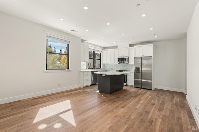 kitchen featuring a kitchen island, white cabinetry, stainless steel appliances, and light hardwood / wood-style flooring