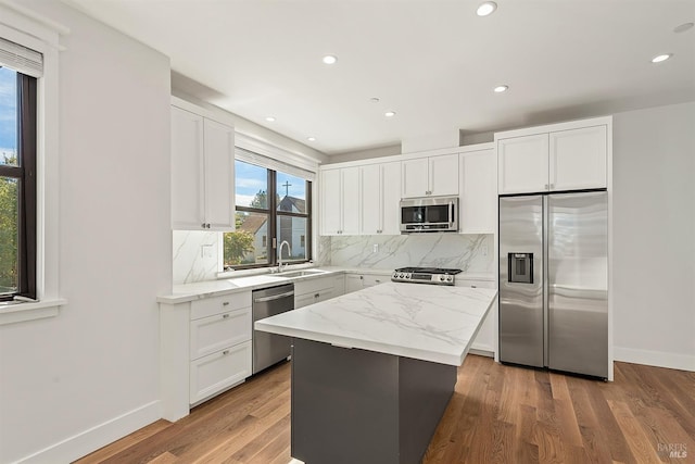 kitchen featuring a kitchen island, wood-type flooring, sink, white cabinetry, and appliances with stainless steel finishes