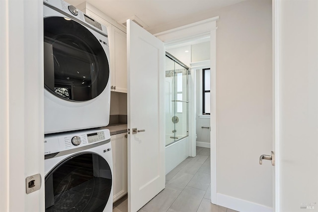 clothes washing area featuring light tile patterned floors and stacked washer / drying machine