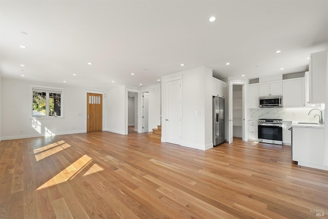 unfurnished living room featuring sink and light wood-type flooring