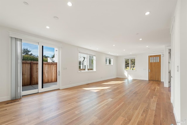 unfurnished living room featuring light wood-type flooring and plenty of natural light