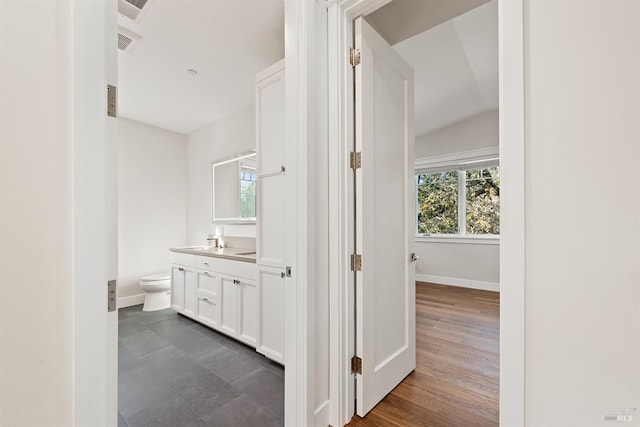 bathroom featuring vaulted ceiling, hardwood / wood-style flooring, vanity, and toilet