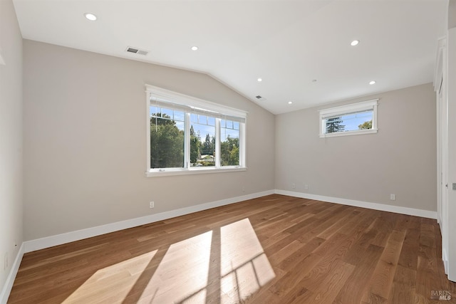 spare room featuring vaulted ceiling and hardwood / wood-style floors