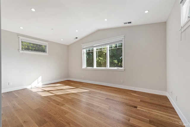 spare room with light hardwood / wood-style floors and vaulted ceiling