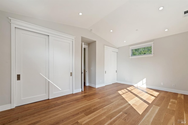 unfurnished bedroom with lofted ceiling and hardwood / wood-style floors