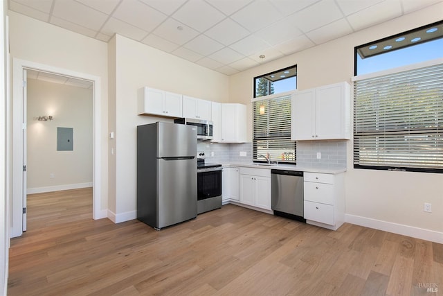 kitchen with white cabinets, sink, light hardwood / wood-style flooring, backsplash, and stainless steel appliances