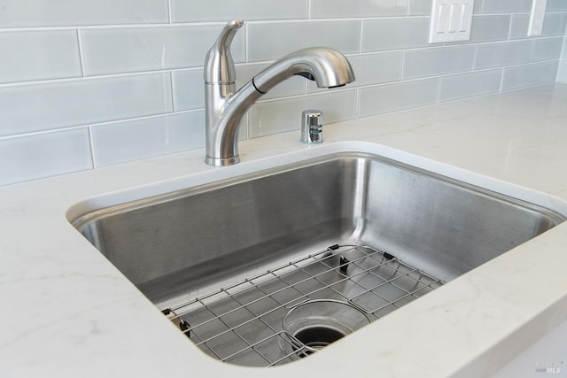 details with light stone counters, sink, and decorative backsplash