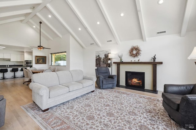 living room with beamed ceiling, light wood-type flooring, high vaulted ceiling, and ceiling fan