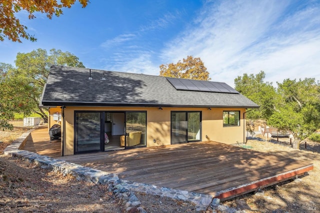 back of house featuring solar panels and a wooden deck