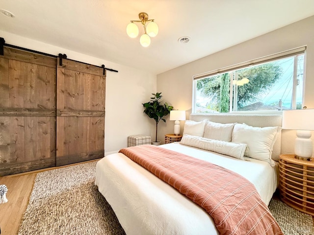 bedroom with a barn door and wood-type flooring