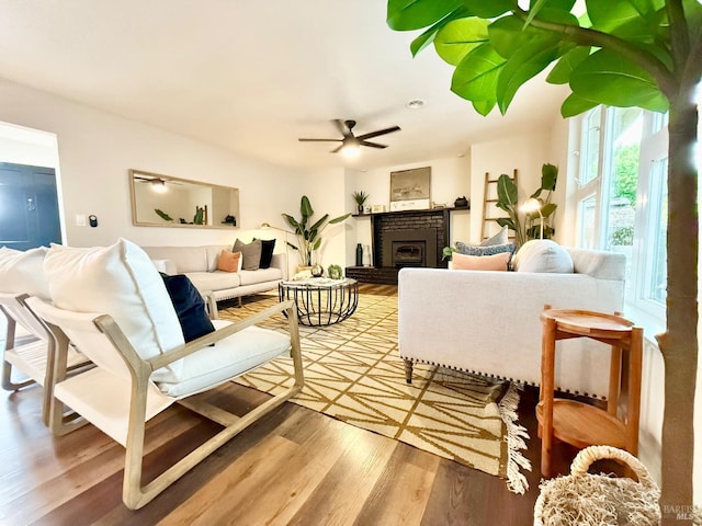 living room with hardwood / wood-style flooring, a brick fireplace, and ceiling fan