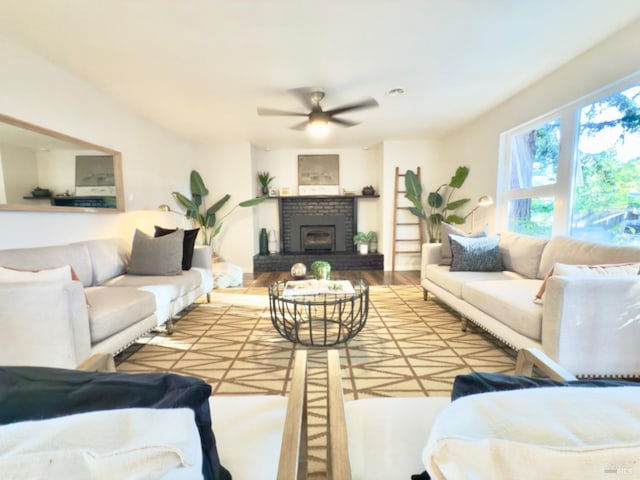 living room with wood-type flooring, a brick fireplace, and ceiling fan