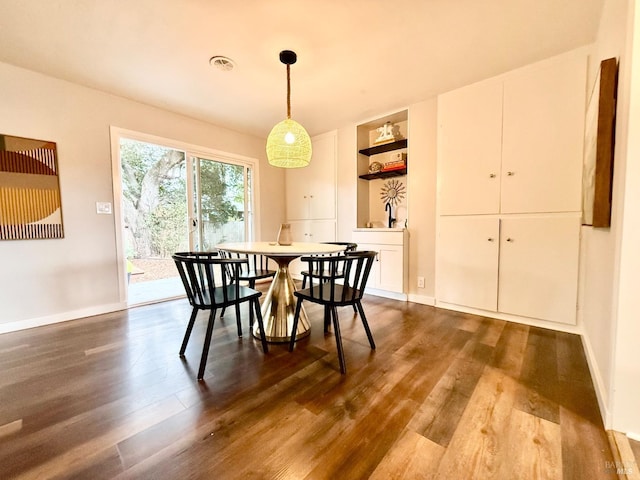 dining area featuring built in shelves and dark hardwood / wood-style flooring