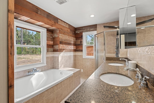 bathroom with tile walls, vanity, and plus walk in shower