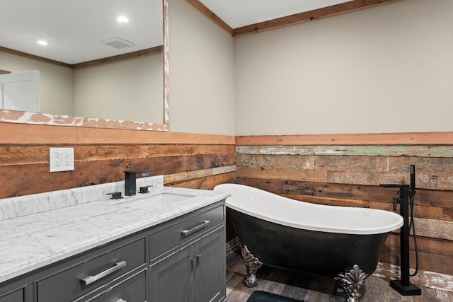 bathroom featuring crown molding, wooden walls, vanity, and a bath