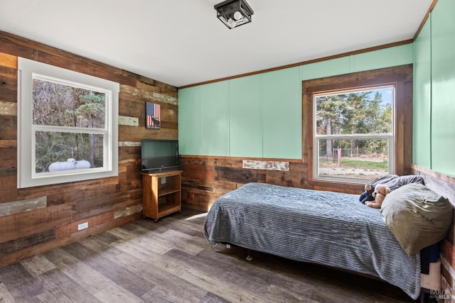 bedroom with crown molding, wooden walls, and dark hardwood / wood-style floors