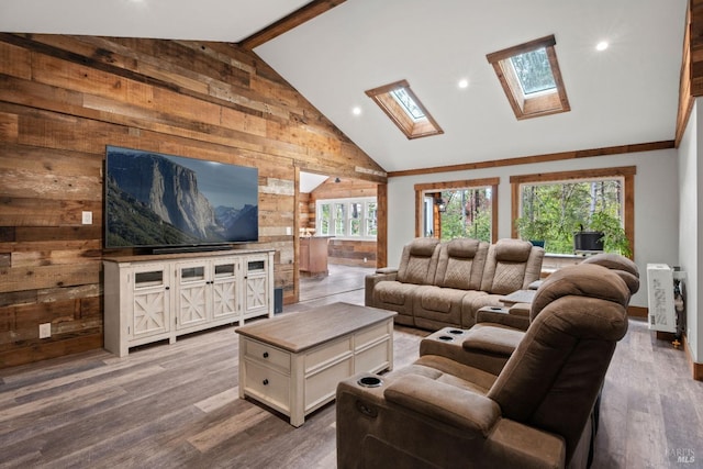 living room with high vaulted ceiling, a skylight, wood walls, wood-type flooring, and beam ceiling