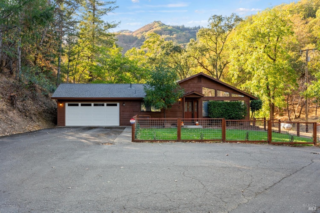 view of front of property featuring a garage, a mountain view, and a front lawn