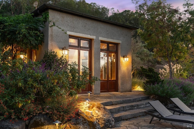 exterior entry at dusk with a patio area and stucco siding