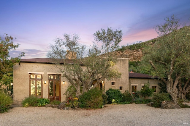 pueblo-style house featuring stucco siding and a chimney