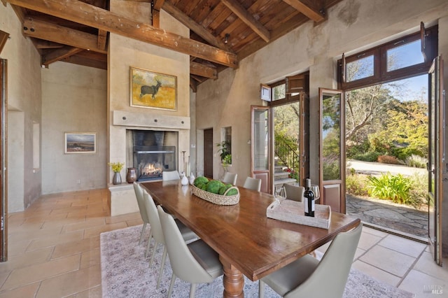 dining room featuring wooden ceiling, beamed ceiling, high vaulted ceiling, and a lit fireplace