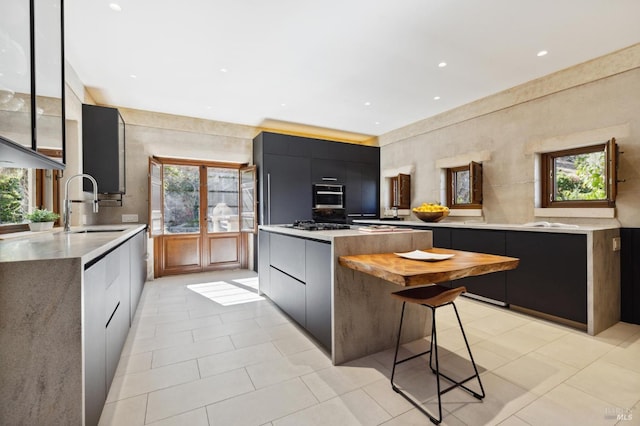 kitchen with oven, modern cabinets, light countertops, and a sink