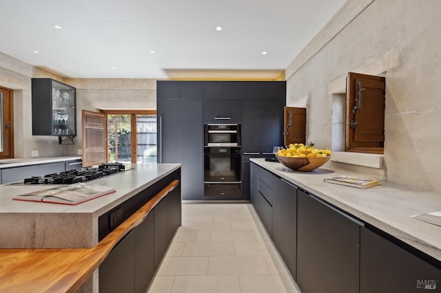 kitchen featuring stainless steel gas cooktop, modern cabinets, light countertops, and dobule oven black