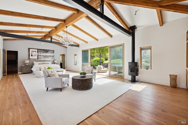 living room featuring baseboards, lofted ceiling with beams, hardwood / wood-style floors, a wood stove, and a notable chandelier