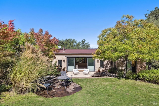 back of property featuring a yard, a patio area, and brick siding