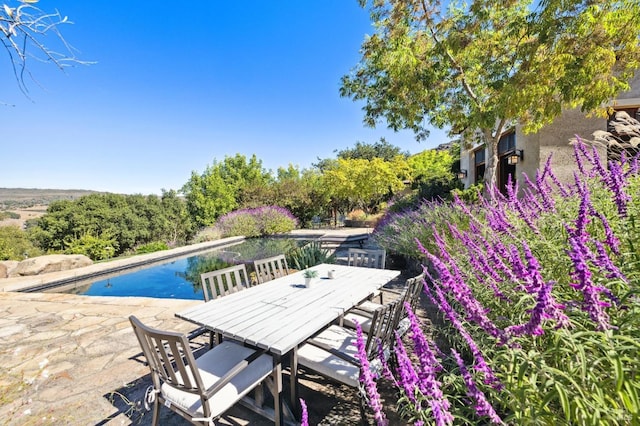 pool featuring a water view, outdoor dining space, and a patio area