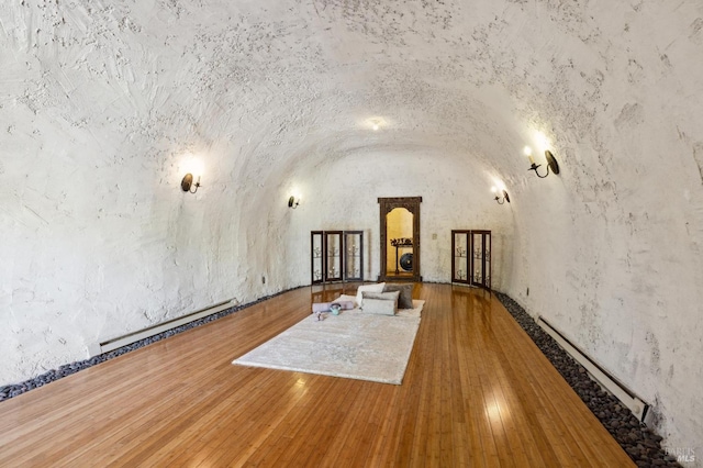 unfurnished living room with lofted ceiling, wood-type flooring, and baseboard heating